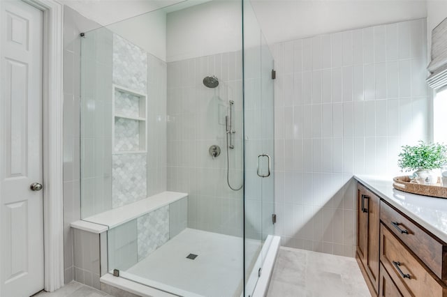 full bathroom with tile patterned floors, vanity, tile walls, and a stall shower