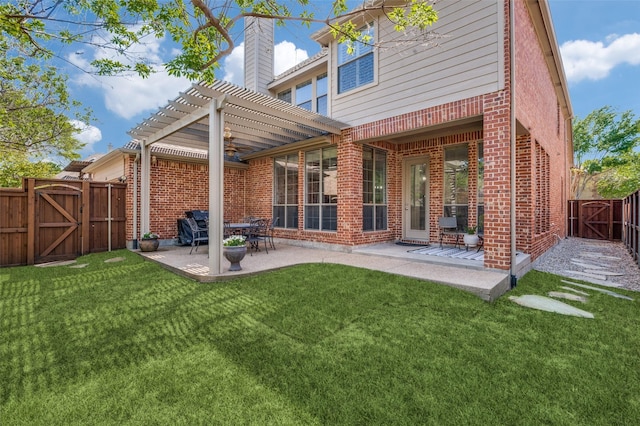 back of property with brick siding, a yard, a gate, and a patio area