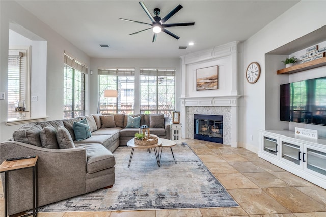 living room with a fireplace, visible vents, and ceiling fan