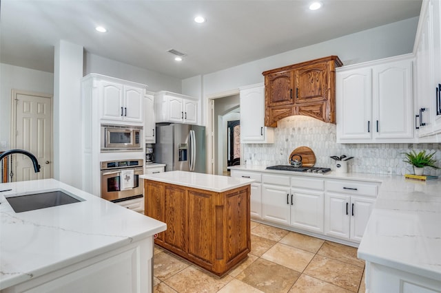 kitchen with visible vents, a center island, a sink, appliances with stainless steel finishes, and decorative backsplash