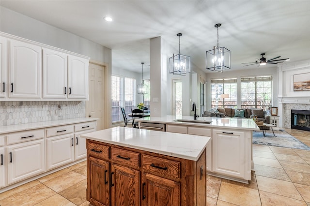 kitchen with ceiling fan with notable chandelier, a glass covered fireplace, a center island, a sink, and backsplash
