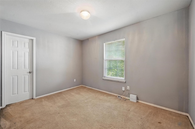 carpeted spare room featuring baseboards