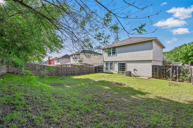 rear view of house featuring a fenced backyard, a yard, and central AC