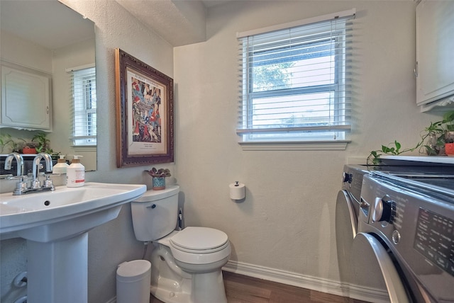 half bath with wood finished floors, baseboards, a wealth of natural light, and washer and clothes dryer