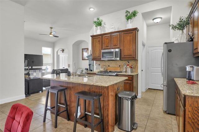 1124 Spanish Moss Dr, Savannah, TX 76227 - kitchen featuring tasteful backsplash, light tile patterned floors, appliances with stainless steel finishes, and arched walkways