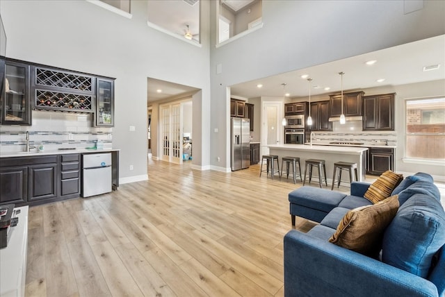 2605 High Bluff Dr, Mansfield, TX 76063 - living area with visible vents, baseboards, a ceiling fan, light wood-style flooring, and wet bar