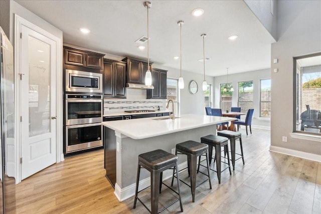 2605 High Bluff Dr, Mansfield, TX 76063 - kitchen featuring stainless steel appliances, light wood-style floors, a sink, and a kitchen bar