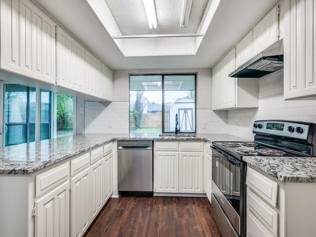 kitchen featuring white cabinetry, under cabinet range hood, a sink, stainless steel appliances, and dark wood-style floors