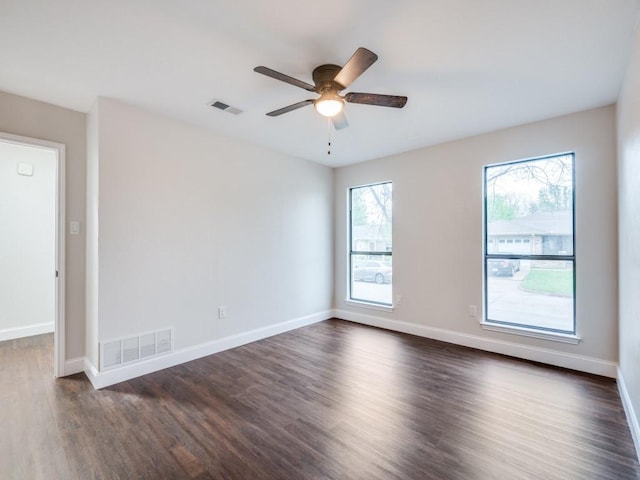 unfurnished room featuring baseboards, dark wood-style flooring, ceiling fan, and visible vents