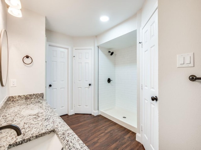 bathroom featuring a tile shower, wood finished floors, and vanity