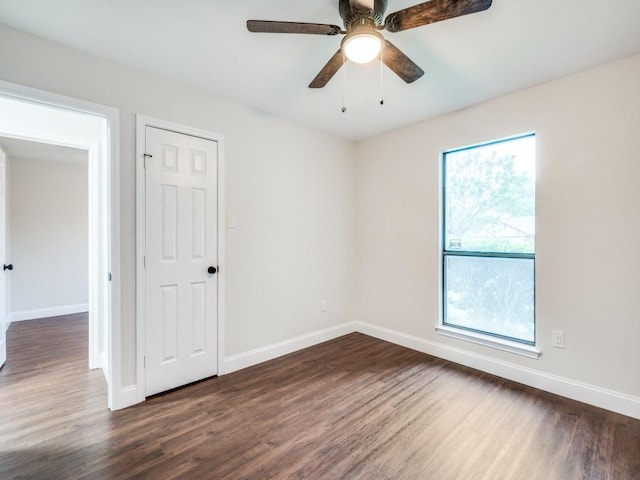 unfurnished room featuring baseboards and dark wood finished floors