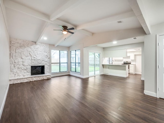 unfurnished living room featuring dark wood-style floors, baseboards, a ceiling fan, and a stone fireplace