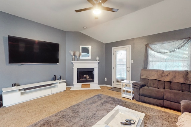 carpeted living room with a fireplace with raised hearth, baseboards, a ceiling fan, and lofted ceiling