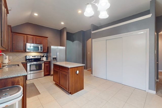 kitchen featuring an inviting chandelier, a sink, stainless steel appliances, backsplash, and a kitchen island