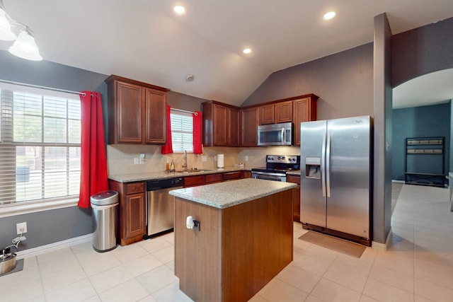 kitchen featuring vaulted ceiling, backsplash, stainless steel appliances, arched walkways, and a sink