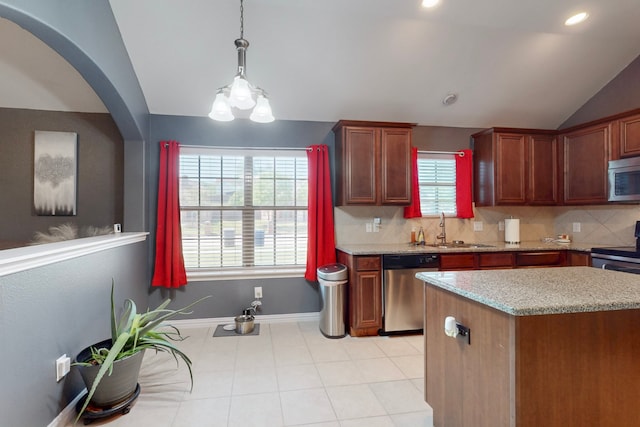 kitchen with vaulted ceiling, backsplash, decorative light fixtures, stainless steel appliances, and a sink
