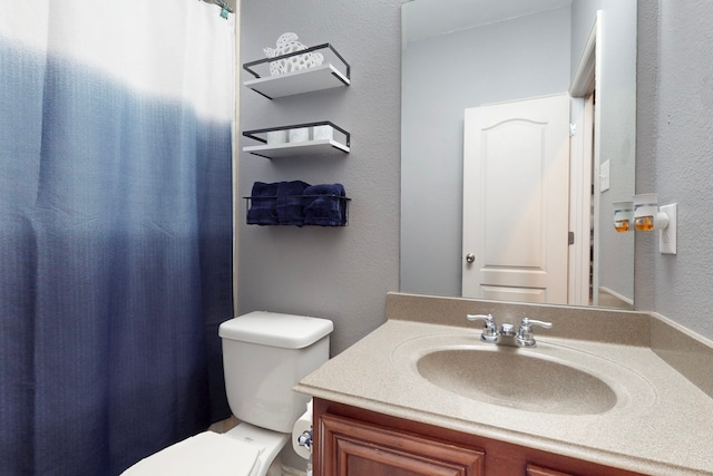 bathroom with toilet, curtained shower, vanity, and a textured wall