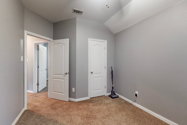 unfurnished bedroom with visible vents, baseboards, carpet, and vaulted ceiling