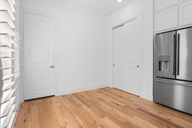 unfurnished bedroom featuring stainless steel fridge, recessed lighting, baseboards, and light wood-style floors