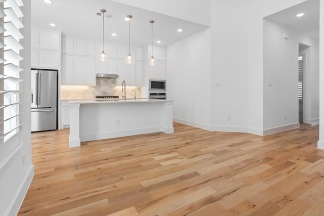 kitchen featuring appliances with stainless steel finishes, light countertops, white cabinets, backsplash, and baseboards