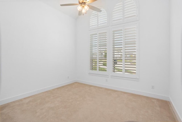 spare room featuring baseboards, light carpet, and ceiling fan