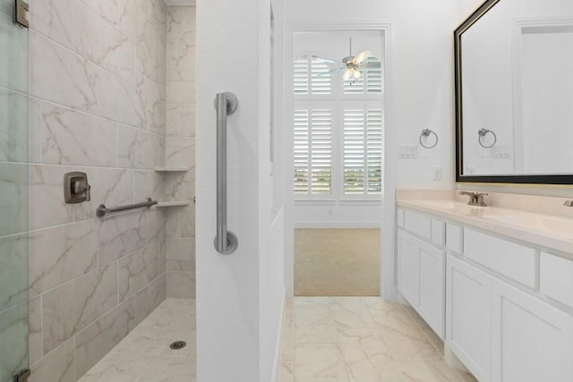bathroom featuring tiled shower, double vanity, marble finish floor, ceiling fan, and a sink