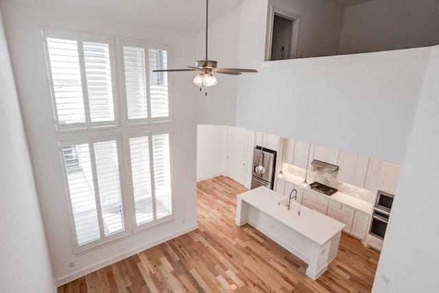 living room with light wood finished floors, ceiling fan, and plenty of natural light