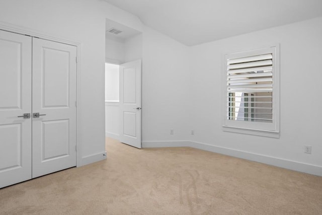 unfurnished bedroom with a closet, visible vents, light carpet, and baseboards