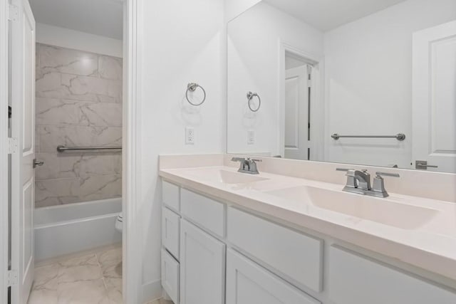 bathroom with marble finish floor, toilet, double vanity, and a sink