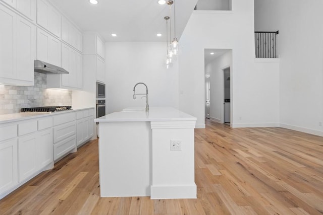 kitchen featuring recessed lighting, under cabinet range hood, decorative backsplash, light countertops, and appliances with stainless steel finishes