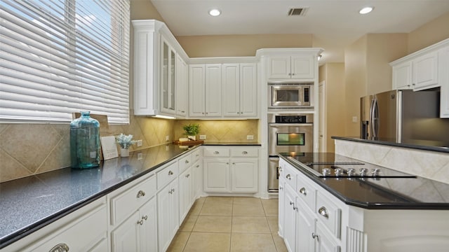 kitchen featuring visible vents, dark countertops, white cabinets, appliances with stainless steel finishes, and backsplash