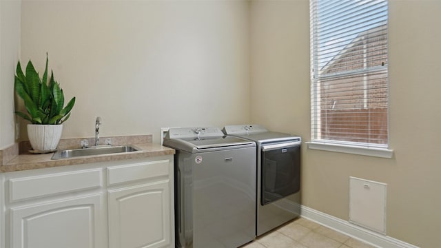 laundry room featuring baseboards, washer and clothes dryer, a sink, cabinet space, and light tile patterned floors