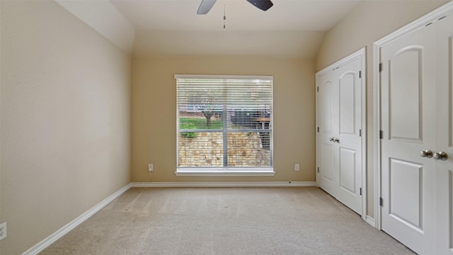 unfurnished bedroom featuring baseboards, ceiling fan, vaulted ceiling, and light carpet