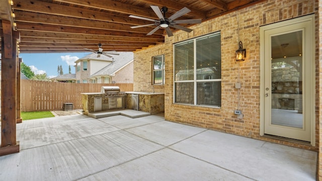 view of patio featuring a ceiling fan, a fenced backyard, and an outdoor kitchen