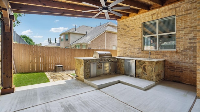 view of patio / terrace featuring ceiling fan, a sink, a grill, a fenced backyard, and an outdoor kitchen