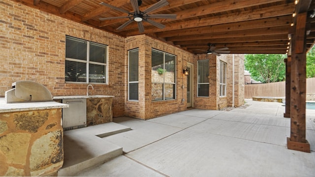 view of patio featuring grilling area, an outdoor kitchen, a ceiling fan, and a fenced backyard