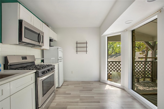 626 N Hampton Rd, Dallas, TX 75208 - kitchen with baseboards, light wood-type flooring, white cabinetry, stainless steel appliances, and backsplash