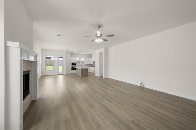 424 Lamb Ln, Waxahachie, TX 75167 - unfurnished living room featuring light wood finished floors, a brick fireplace, a ceiling fan, visible vents, and baseboards