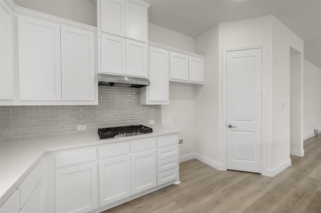 424 Lamb Ln, Waxahachie, TX 75167 - kitchen with stainless steel gas stovetop, under cabinet range hood, light wood-style flooring, baseboards, and white cabinets