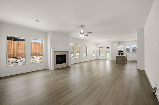 424 Lamb Ln, Waxahachie, TX 75167 - unfurnished living room with wood finished floors, a glass covered fireplace, baseboards, visible vents, and a ceiling fan