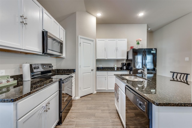kitchen with white cabinets, a sink, an island with sink, black appliances, and light wood finished floors