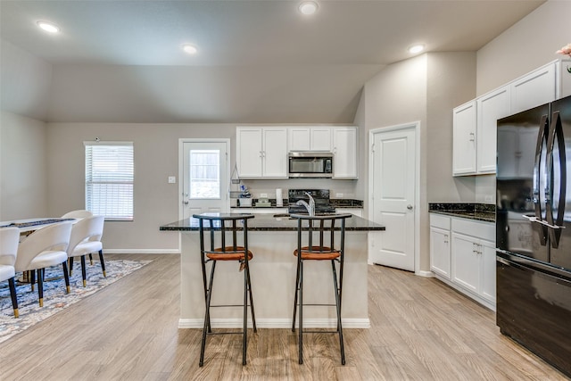 kitchen featuring light wood-type flooring, stainless steel microwave, white cabinets, and freestanding refrigerator
