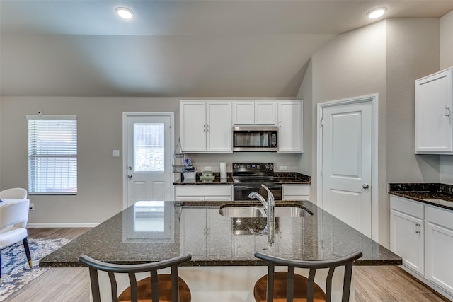 kitchen featuring a sink, stainless steel microwave, black electric range, and a kitchen breakfast bar