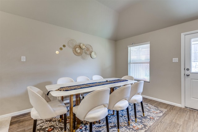 dining area with baseboards, light wood-style floors, and lofted ceiling