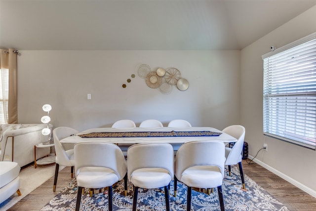 dining room with a wealth of natural light, baseboards, wood finished floors, and lofted ceiling