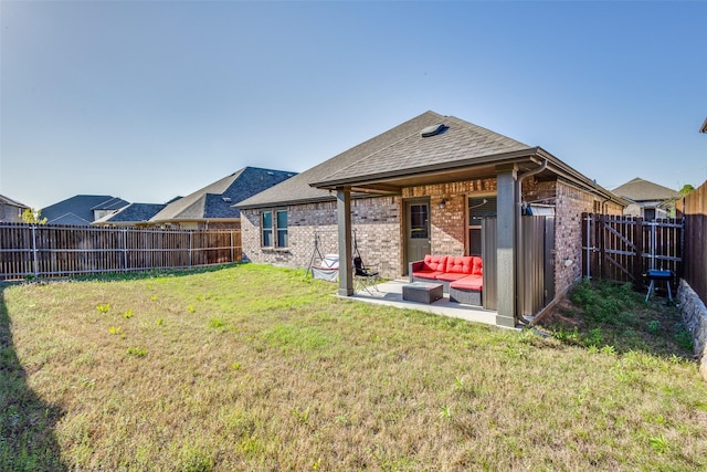 back of property with a yard, a fenced backyard, brick siding, and a patio