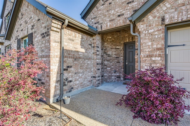 property entrance featuring brick siding and a garage