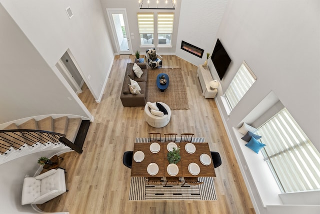 4120 Sandhills Ln, Prosper, TX 75078 - living room featuring wood finished floors, a glass covered fireplace, a towering ceiling, and baseboards