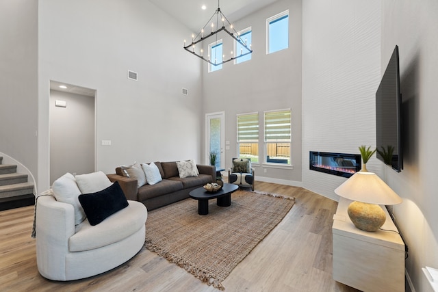 4120 Sandhills Ln, Prosper, TX 75078 - living area featuring wood finished floors, stairs, a high ceiling, a chandelier, and a large fireplace