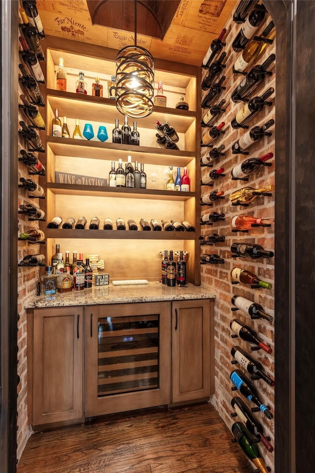 6405 Carmel Falls Ct, Mckinney, TX 75072 - wine cellar with brick wall, a dry bar, dark wood-style floors, and beverage cooler